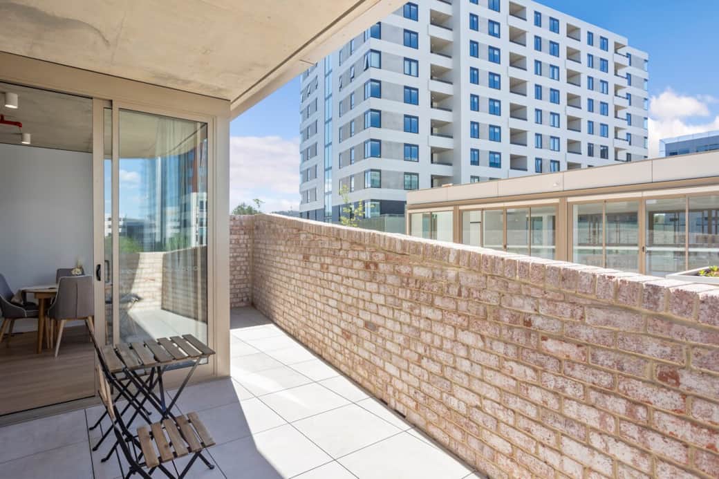 Step outside into your personal oasis, where the brick wall provides a sense of privacy and the clear blue sky invites relaxation. This balcony is an extension of your living space, designed for leisure and enjoyment.