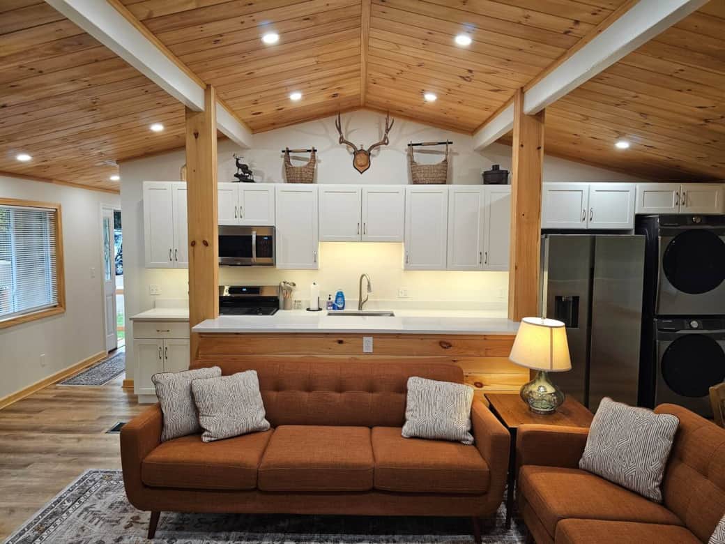 Step into a bright, modern-rustic space with a tongue-and-groove ceiling, warm beams, and dimmable lighting. Enjoy quartz counters, white cabinetry, stainless appliances, and mid-century sofas in the open living area.