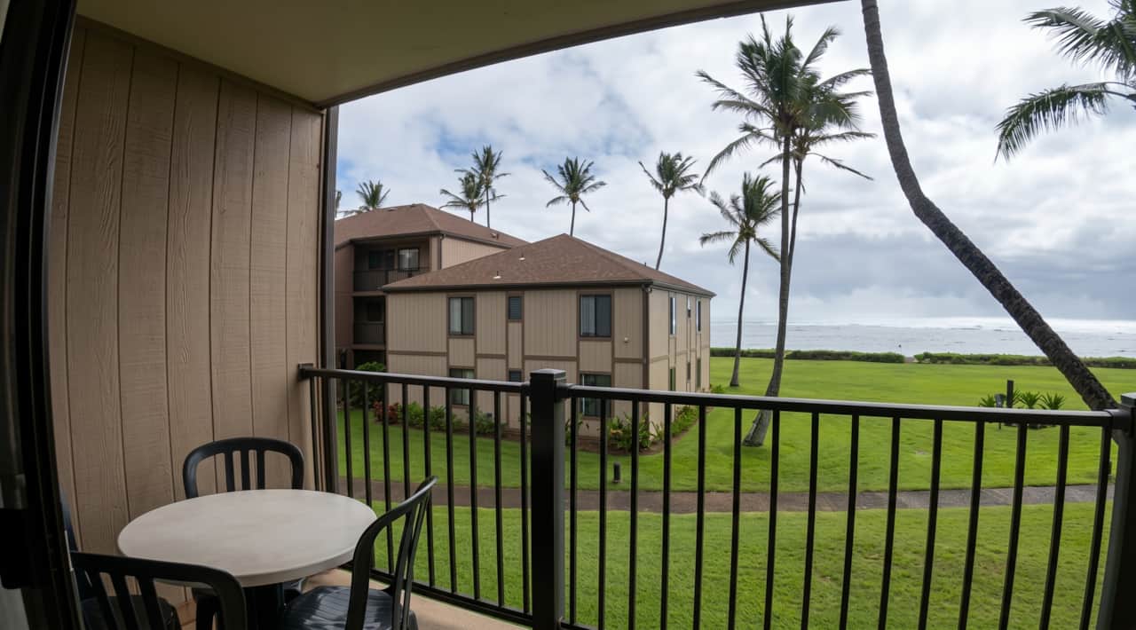 Private lanai with outdoor seating overlooking lush grounds and the ocean beyond.