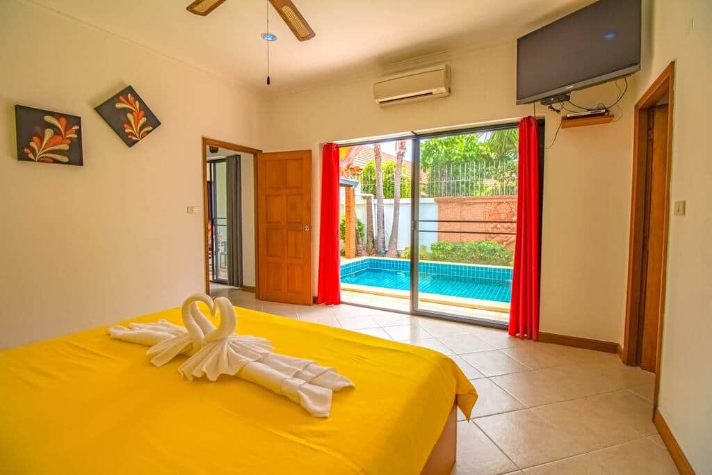La chambre parentale avec sa TV et l'air conditionné, vue sur la piscine