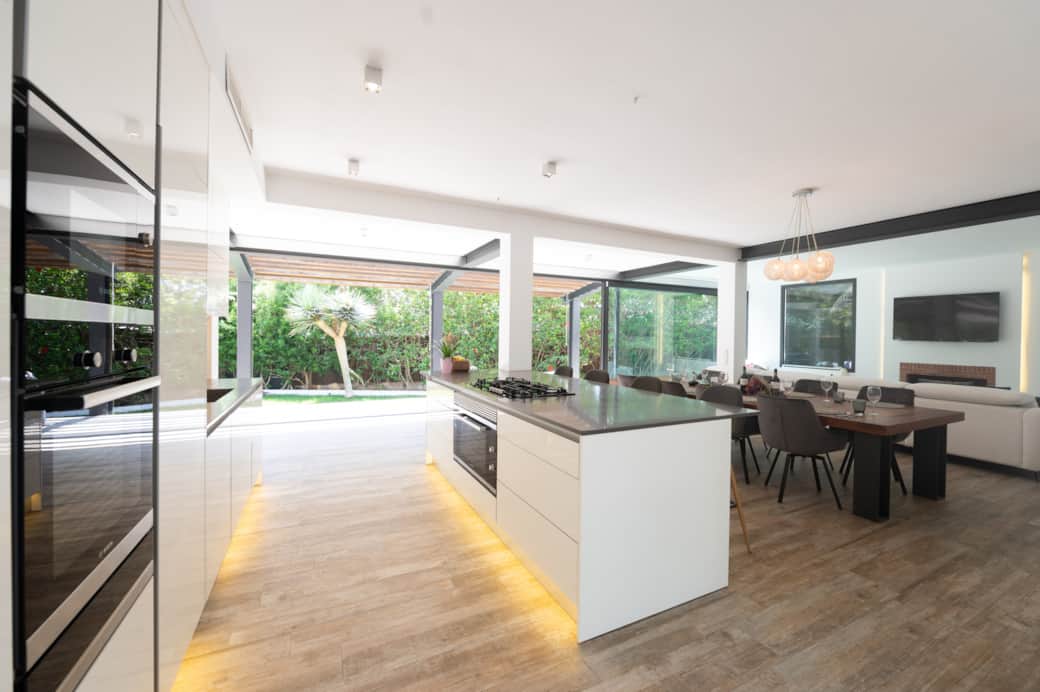 Modern kitchen island and dining area with garden views at Casa Guindilla in Portals Nous, Mallorca