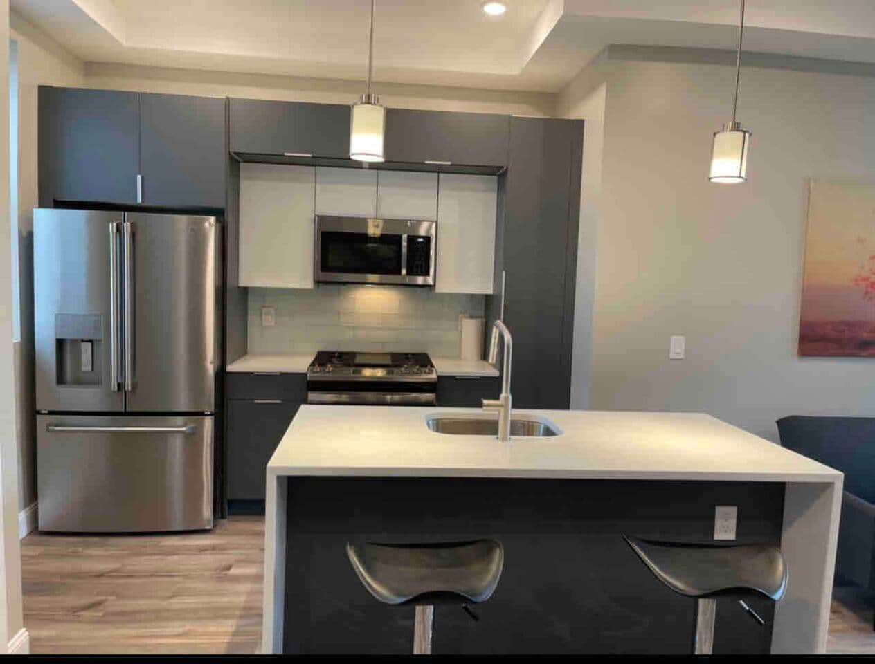 Fully equipped kitchen featuring a large stainless steel refrigerator, a dishwasher, oven, & a microwave.
The elegant granite waterfall island with bar stools, with all your everyday kitchen essentials.  
Also a Keurig coffee Mechine. 