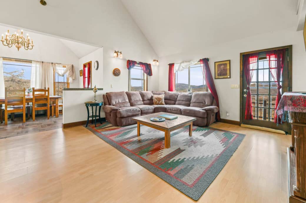 Relax in the spacious main living room filled with natural light and mountain views, complete with a cozy L-shaped sofa, fireplace, and Smart TV, offering the perfect place to gather after adventure-filled days in Park City and Summit County.
