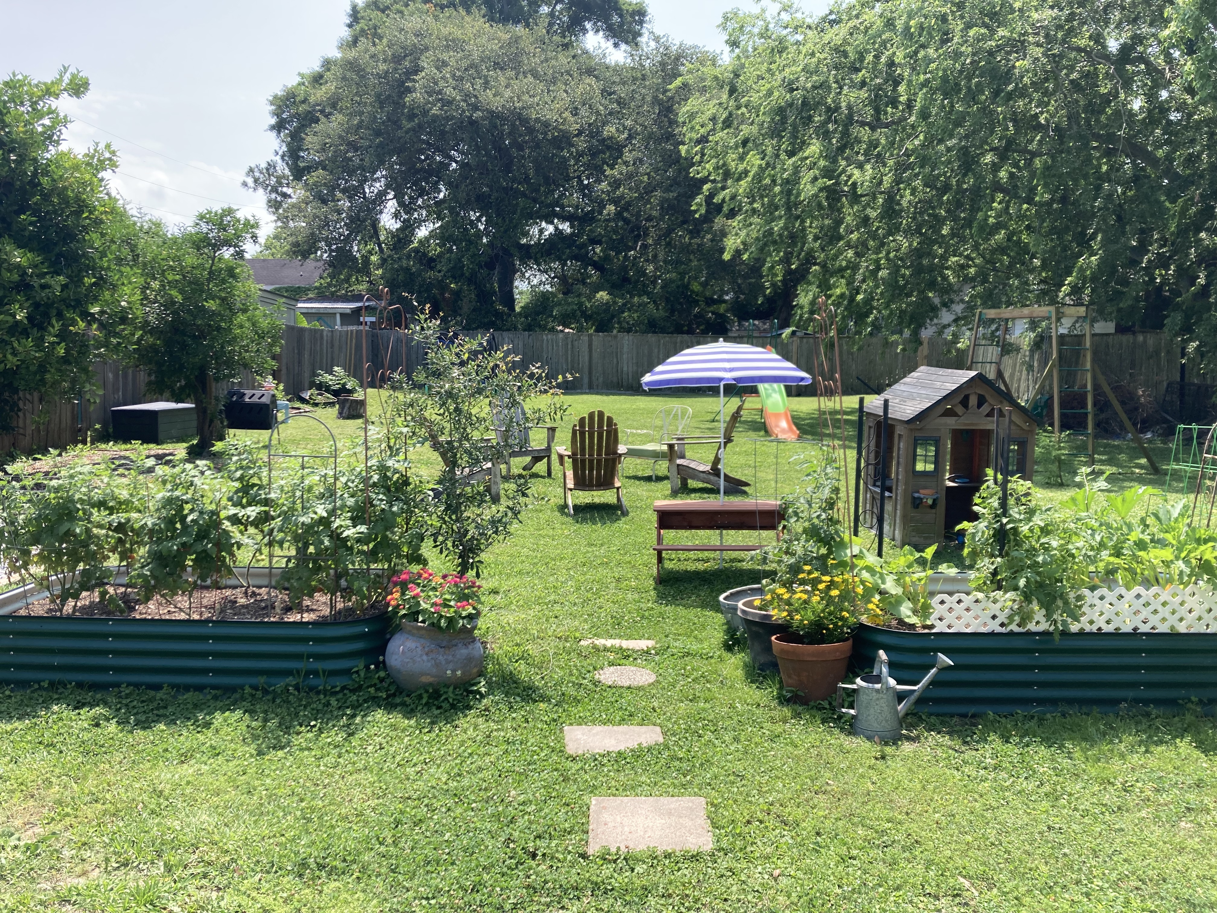 A garden area with raised beds, a playhouse, and outdoor seating.