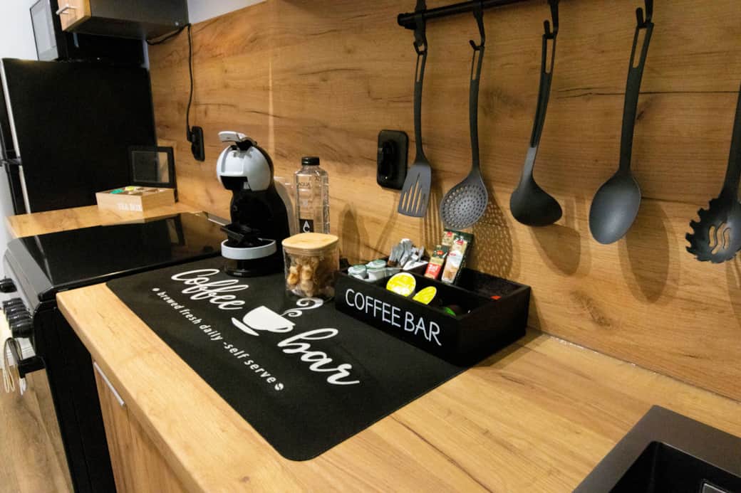 Self-serve coffee bar with capsule machine, condiments tray, and full cooking utensil set