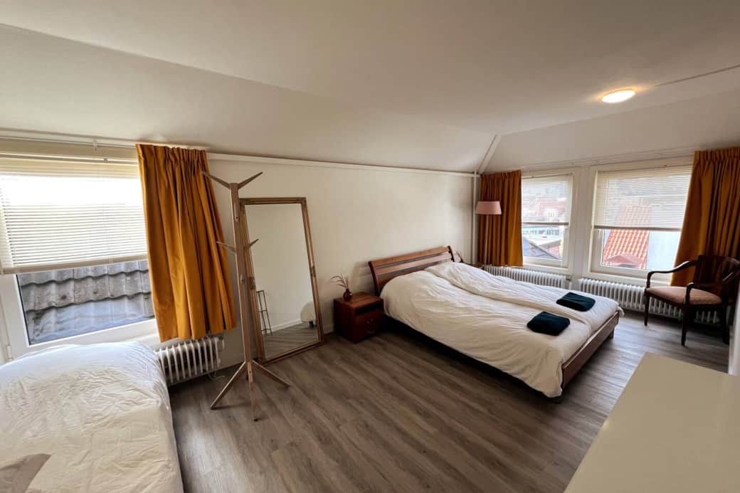 Ruime slaapkamer voorzien van een tweepersoonsbed en een afzonderlijk eenpersoonsbed.
