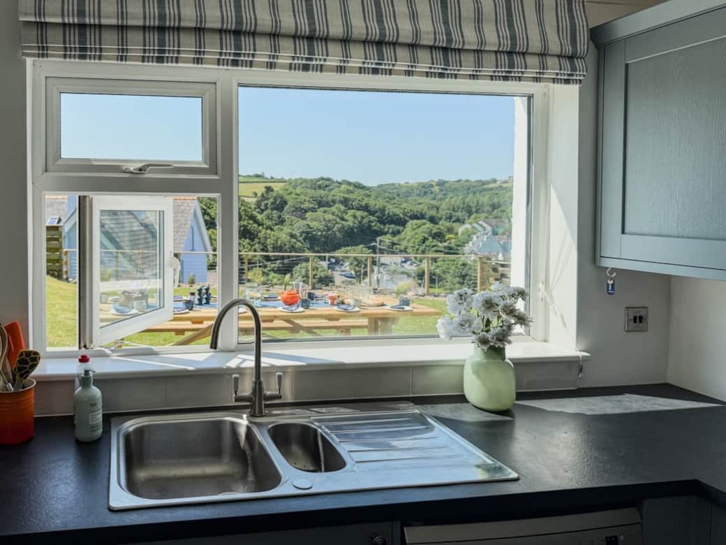 A great view from the kitchen looking beyond the outdoor table and garden to the woods and fields. 