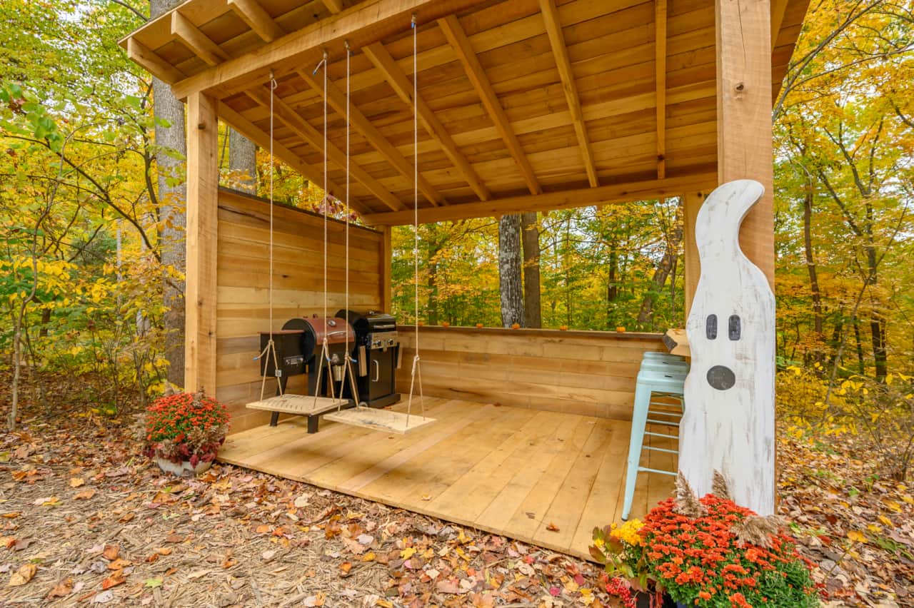 BBQ shed complete with a Pittboss Smoker and a Charbroil propane grill perfect for grilling and outdoor fun.  2 swings for adult relaxation and a live edge bar with 3 metal stools facing the forest views. 
