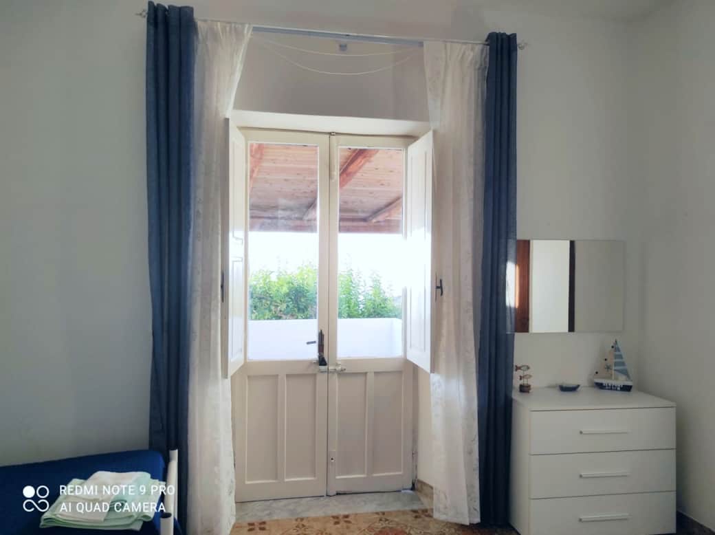 Porta finestra sul patio, luce naturale e atmosfera marina a Casetta Faraglione