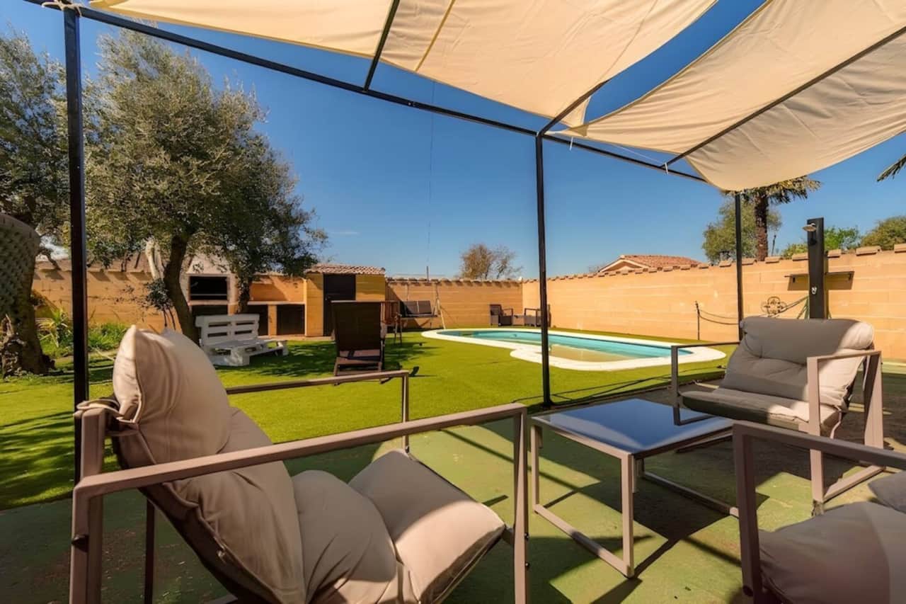 Porche cubierto con sofás exteriores frente a la piscina.