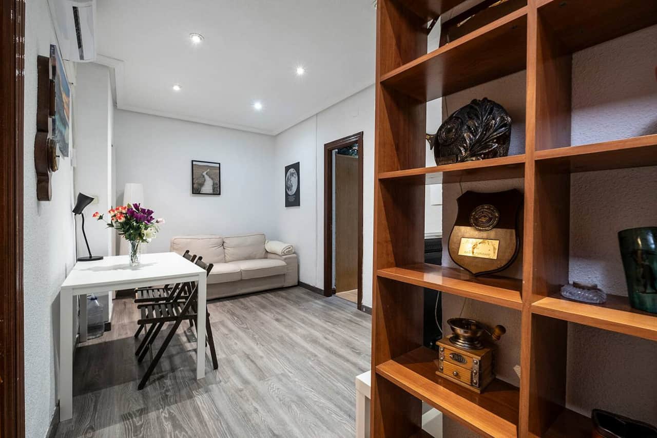 Salón con sofá, mesa plegable y estantería de madera