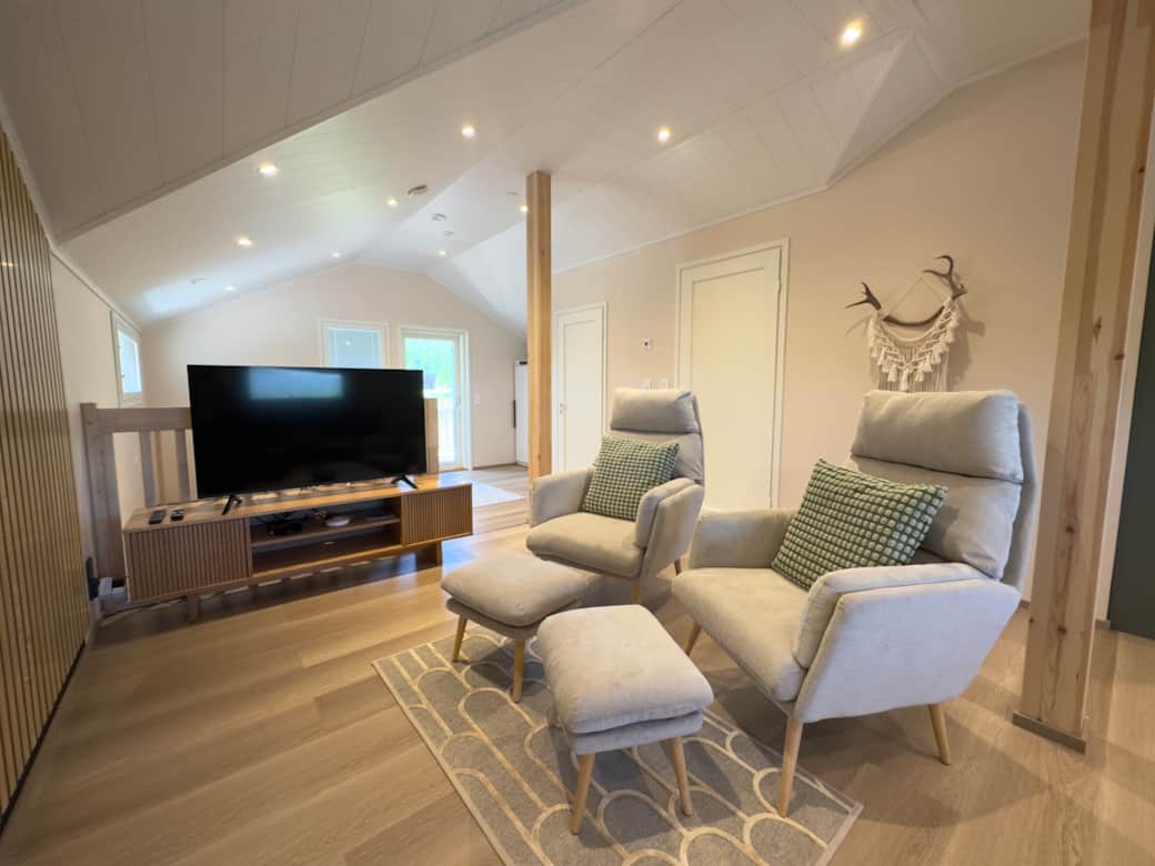 A living room with a big sofa, two armchairs, and a TV