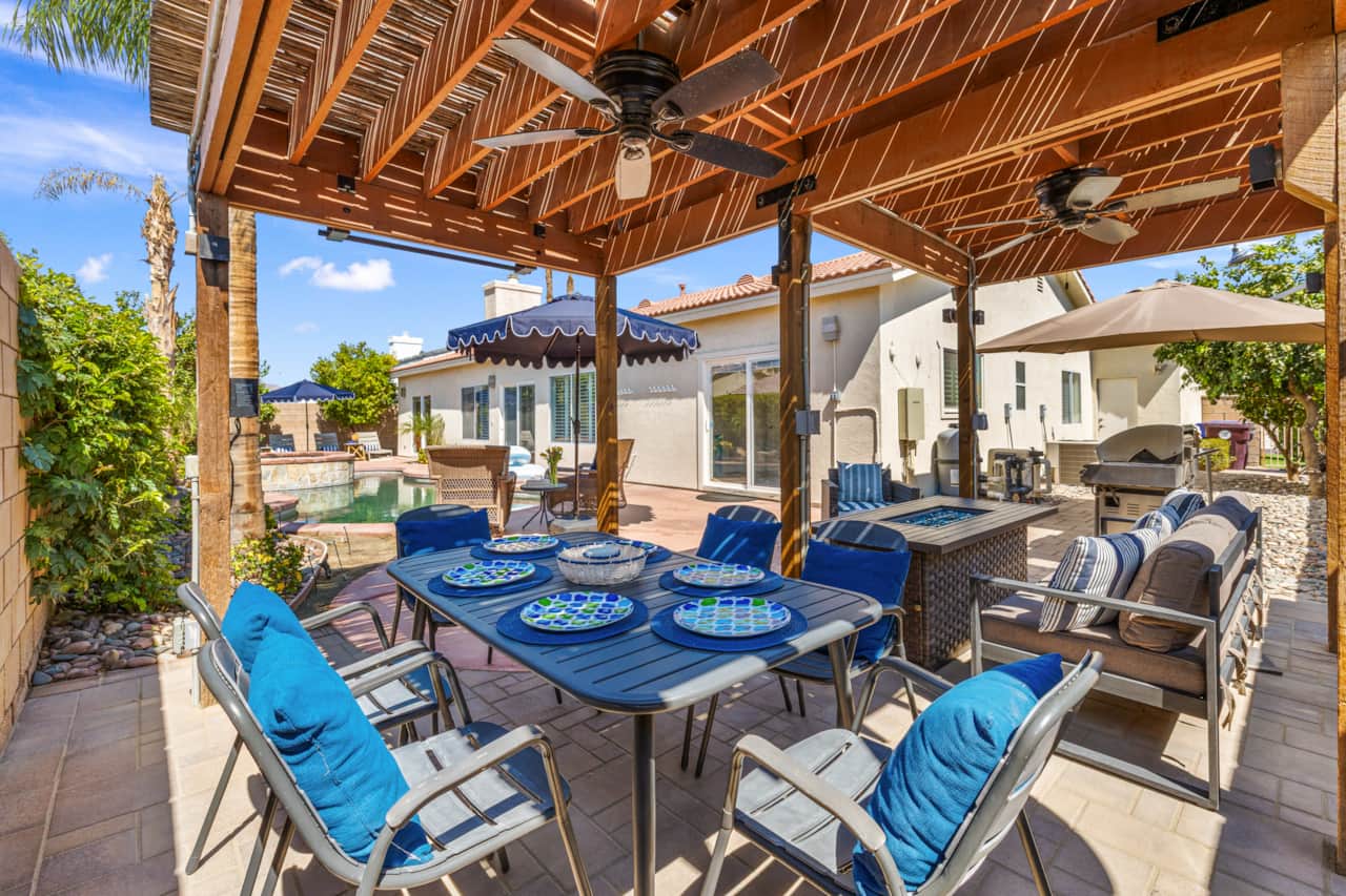 Patio covered al fresco dining adjacent a fire pit 