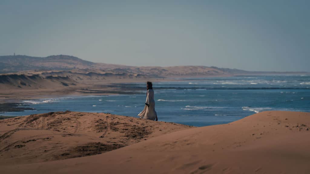 Eine Frau beim Spaziergang durch die Dünen am Meer auf Fuerteventura