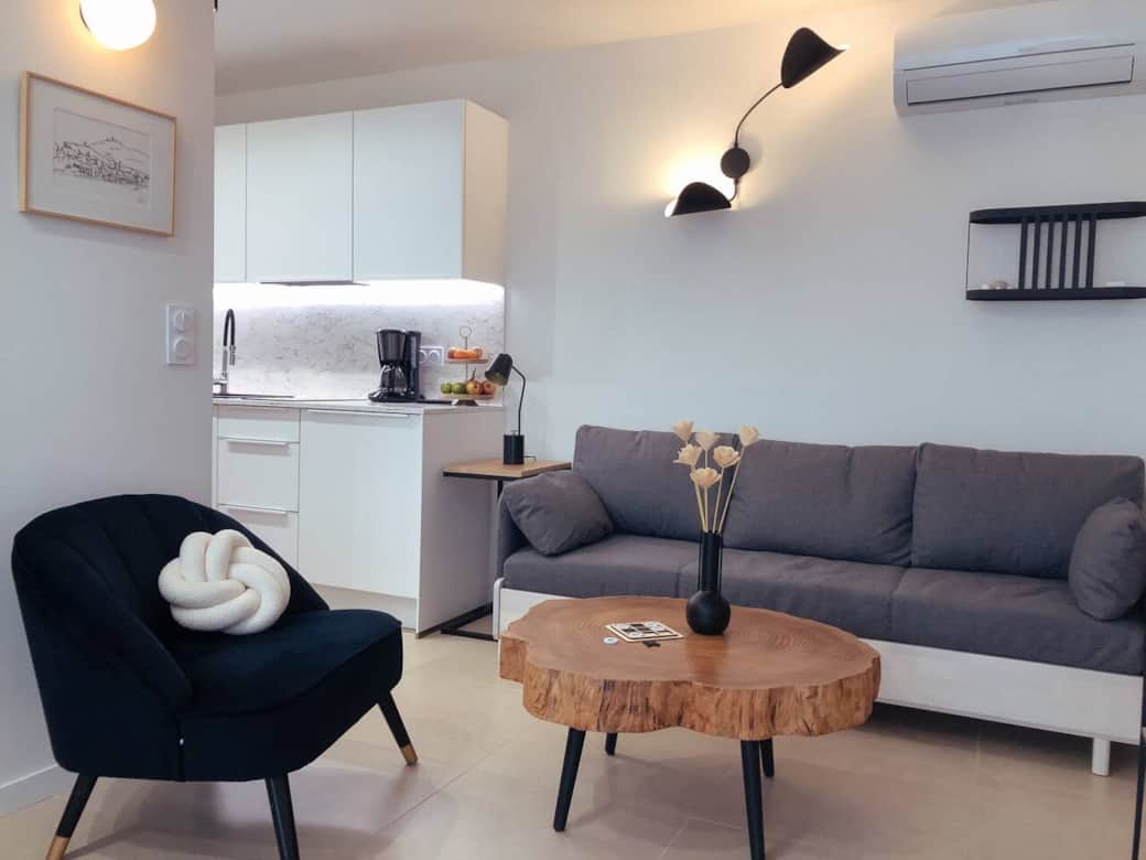  Séjour chaleureux au design soigné avec canapé confortable, fauteuil douillet et table en bois brut . Cuisine ouverte équipée. Climatisation. À 10 min à pied de la plage, du port, du centre historique et à proximité de la gare .
