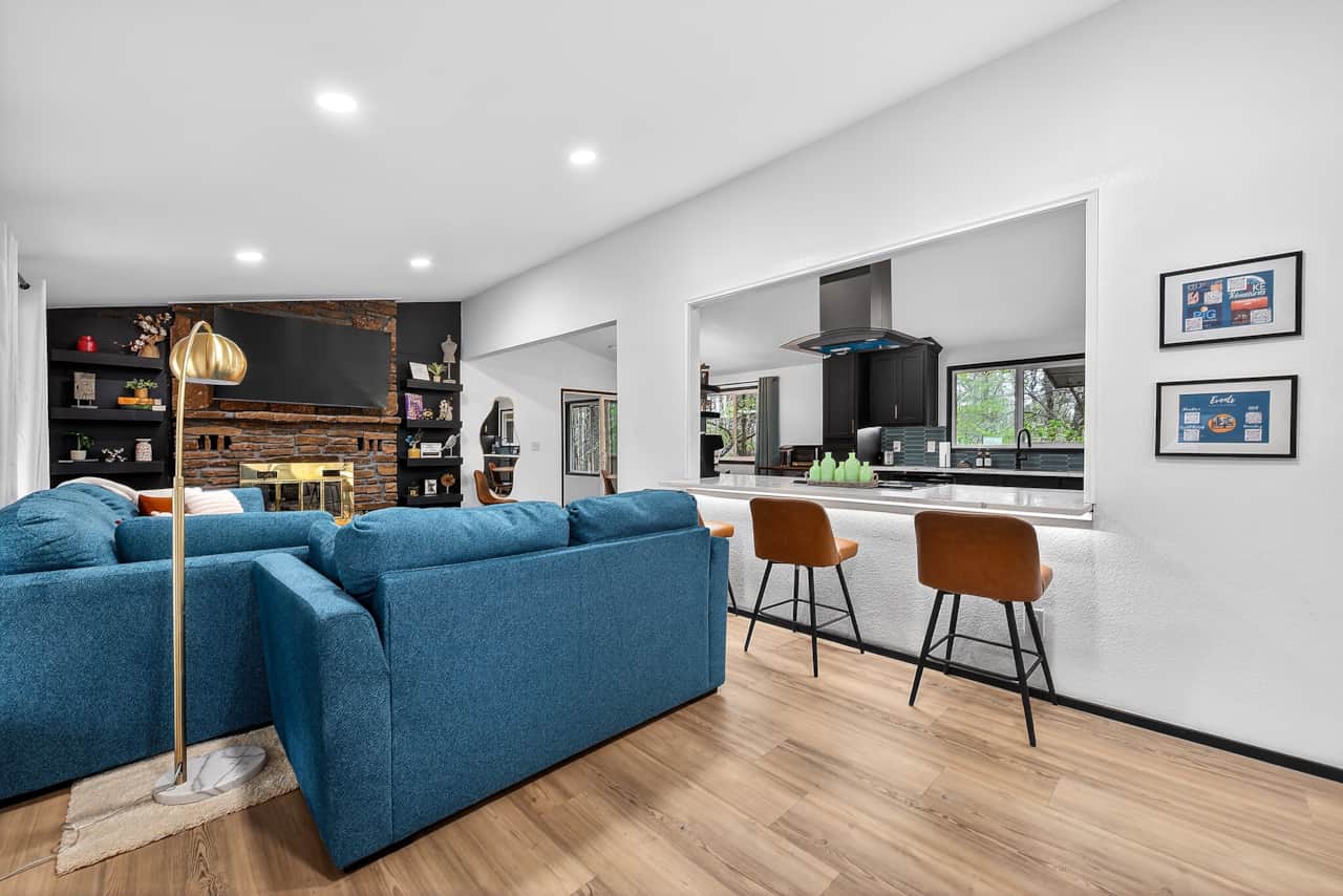 Open living room with comfy sofa, fireplace, and TV, flowing into kitchen and dining areas.
