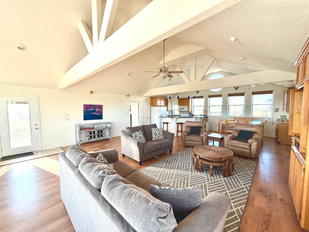 Comfortable sofas and recliners gather around a television while also open to the beach views. Comfortable sofas and recliners gather around a television while also open to the beach views.