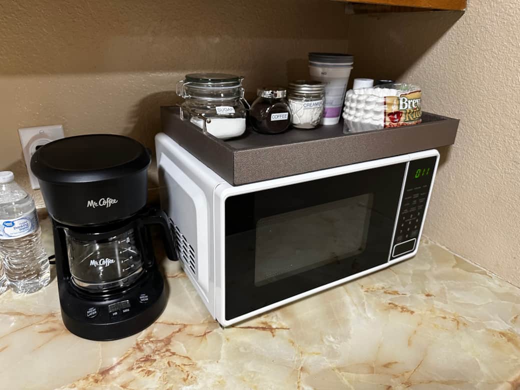 Microwave, coffee maker with coffee, sugar and creamer and coffee filters and to go cups for coffee.