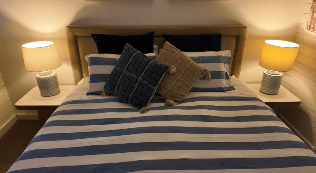 A cozy king sized beautifully styled master bedroom, with soft ambient lighting, neutral tones for a peaceful & intimate rest after a day by the ocean