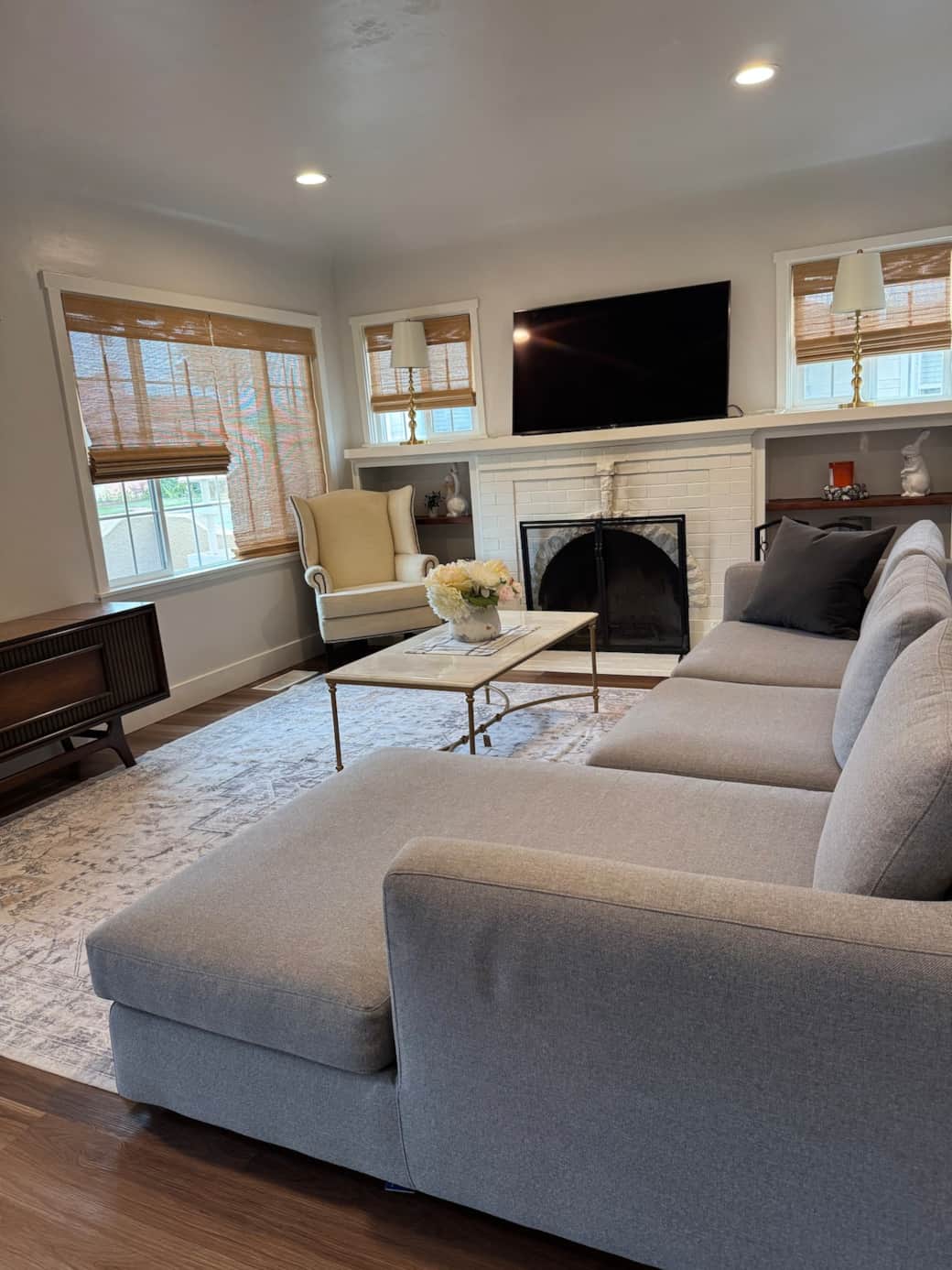 Bright & cozy living room featuring a large, deep EOS cloud sectional, marble coffee table, 55-inch smart TV & Pottery Barn wingback chair.