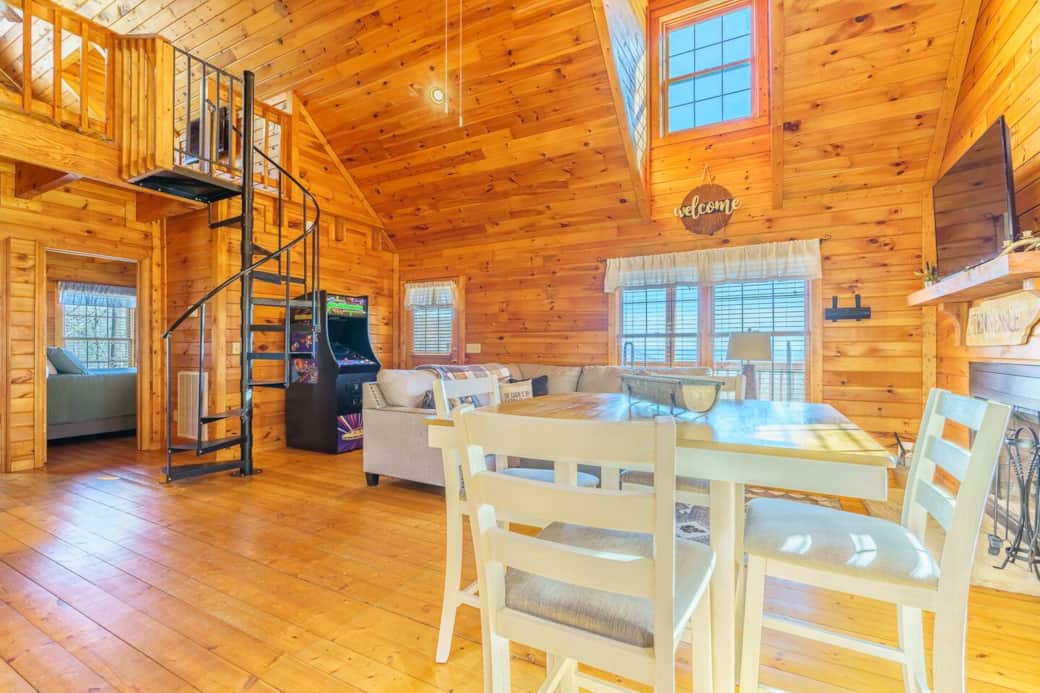 High Top dining area with 4 seats, an overview of the cozy living room and a peak up to the loft area.