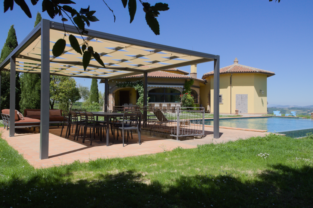 Pergola adiacente alla piscina con tavolo da pranzo, divani e lettini