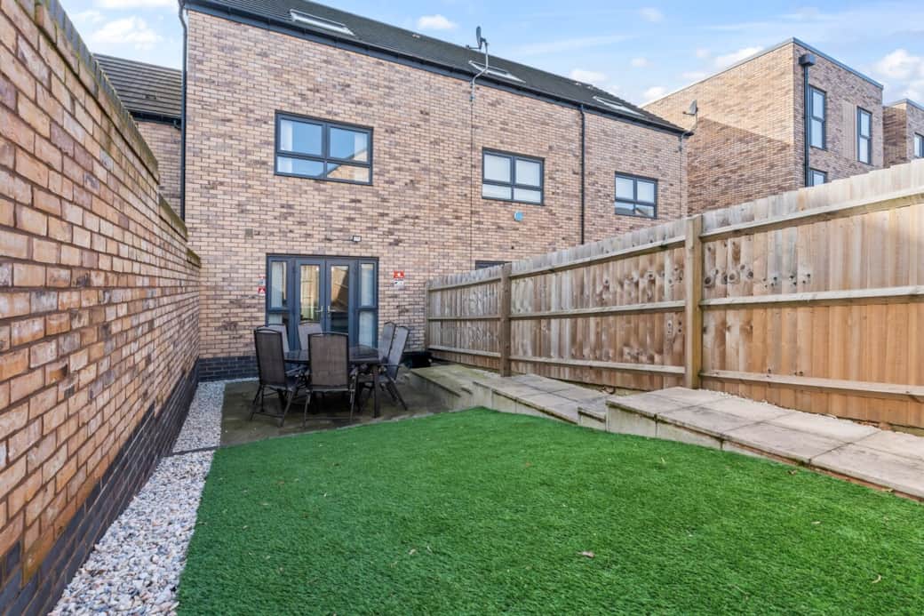 Spacious private back garden in Birmingham featuring a generous patio dining area and large artificial lawn — perfect for relaxing, outdoor meals, or sunbathing during warmer months. An outdoor space ideal for families, contractors, corporate teams.