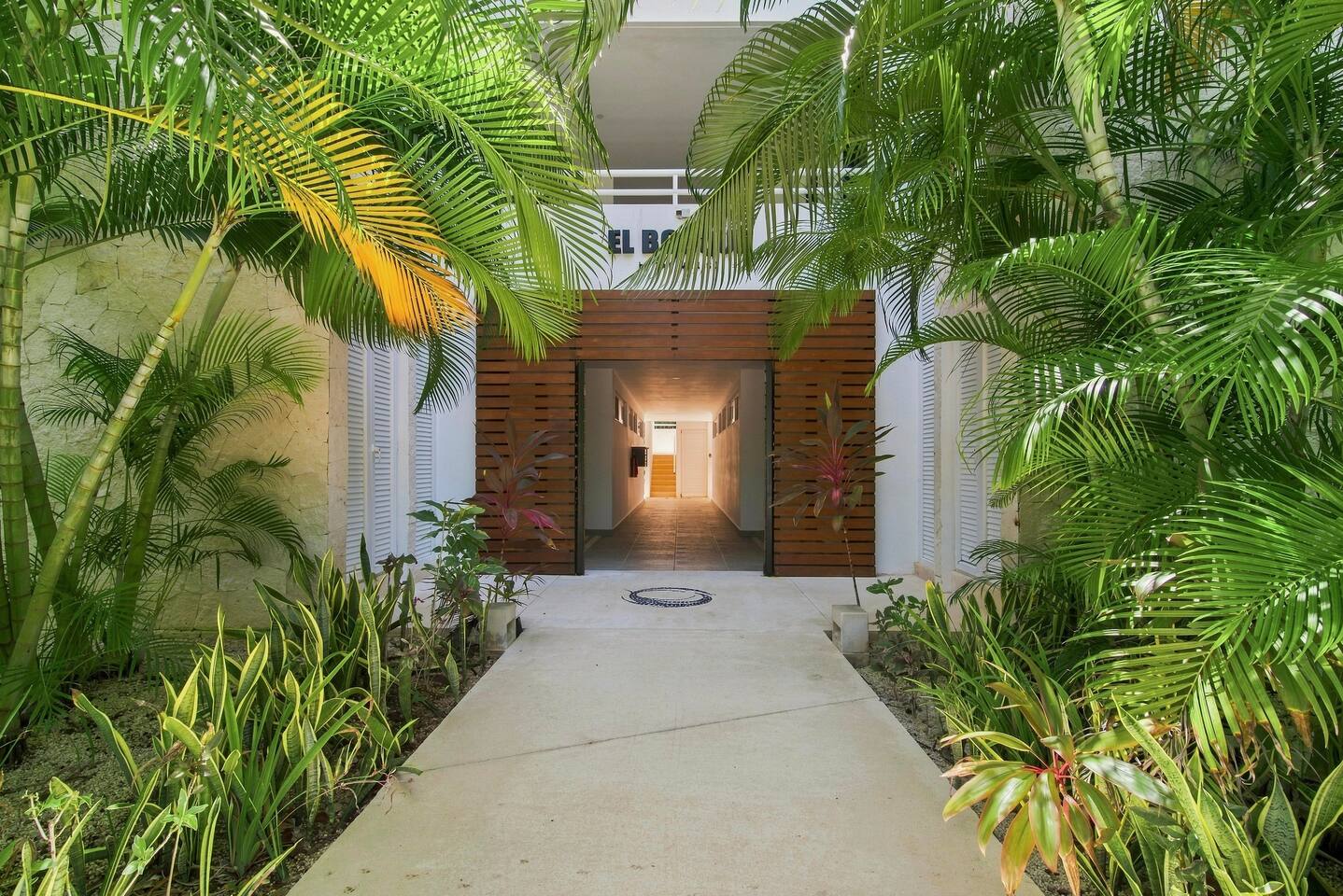 ¡Bienvenidos a El Bosque by TAO! Exuberantes palmeras, vegetación tropical y cálidos detalles de madera enmarcan la entrada, marcando el tono para una estancia relajante rodeada de naturaleza.
