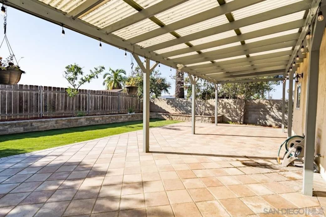 Spacious covered patio with tile flooring and lush backyard—perfect for outdoor living. 