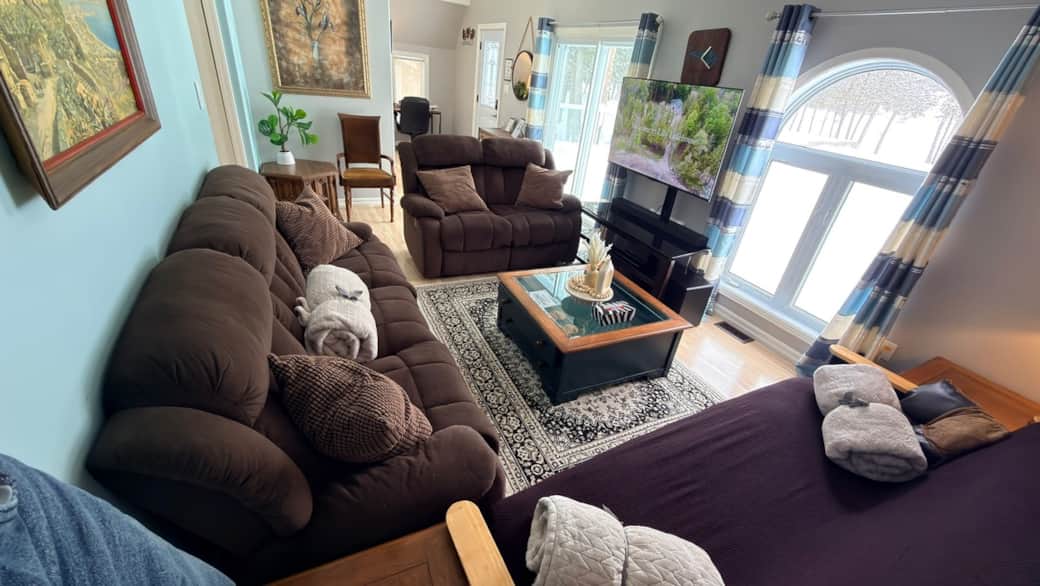 Spacious gathering area with two reclining sofas, one sofa bed, soft throws, and inviting lighting—p