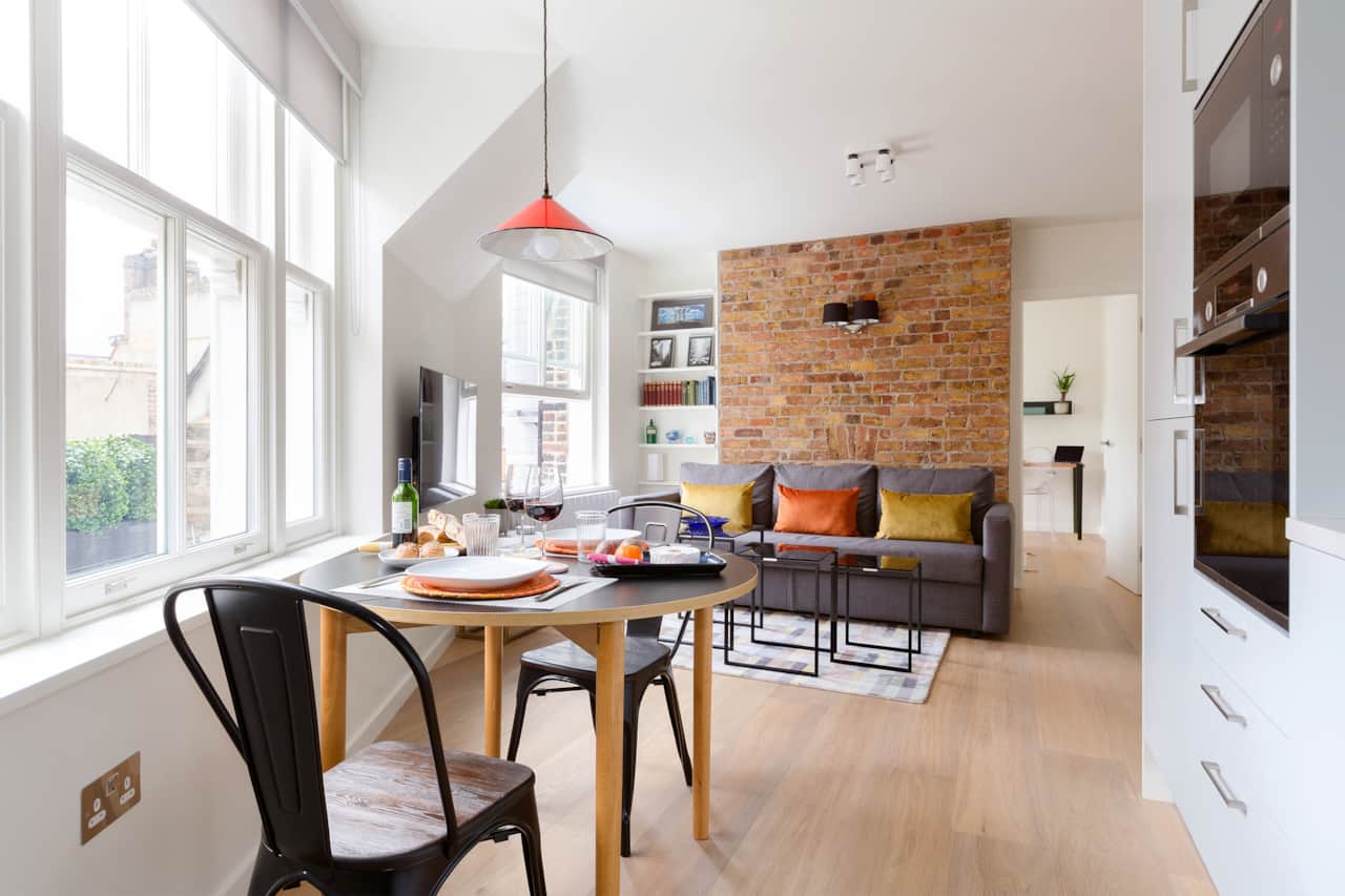 Dining table set for two, with sofa and exposed brick feature wall
