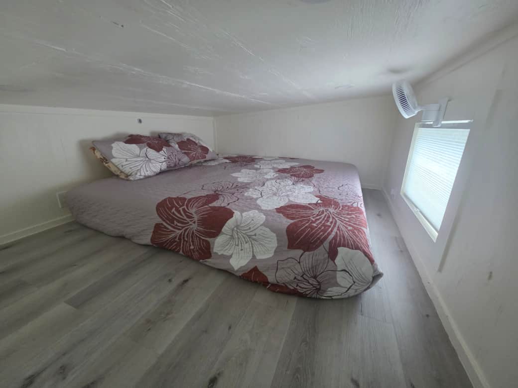 King bed in the loft with a fan and natural light. Great view of the projector screen!