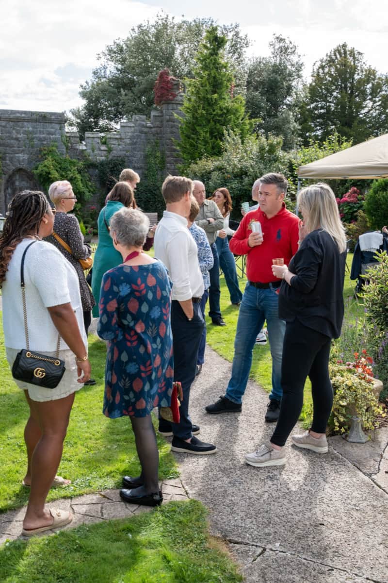 A group of guests chatting on the garden path at a party