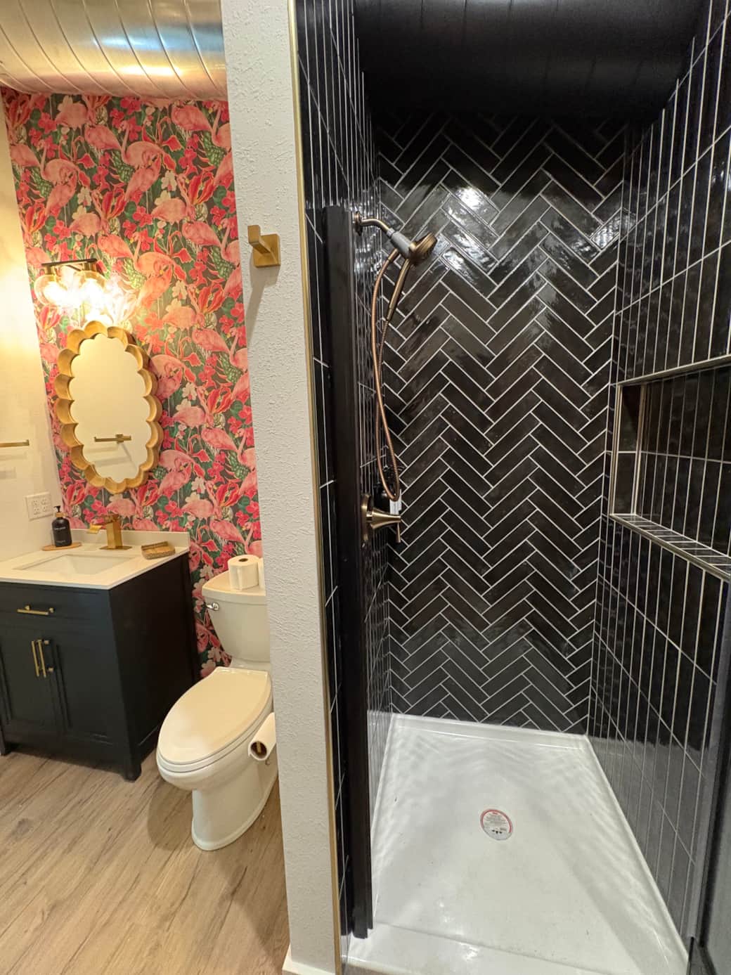 Moody bathroom with flamingo accents and black tiled shower.