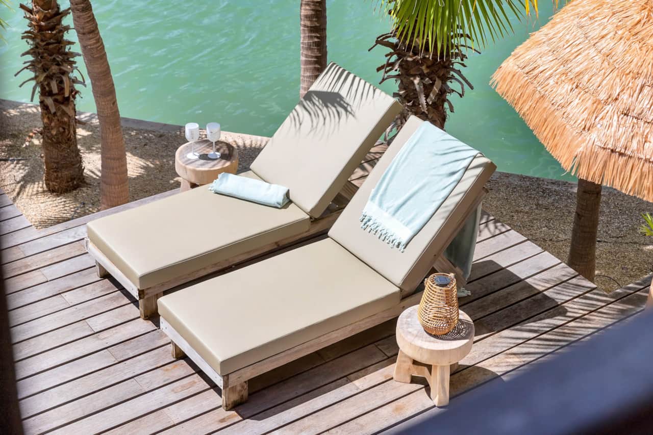Villa Paradiso waterfront sun loungers with tropical palm tree view