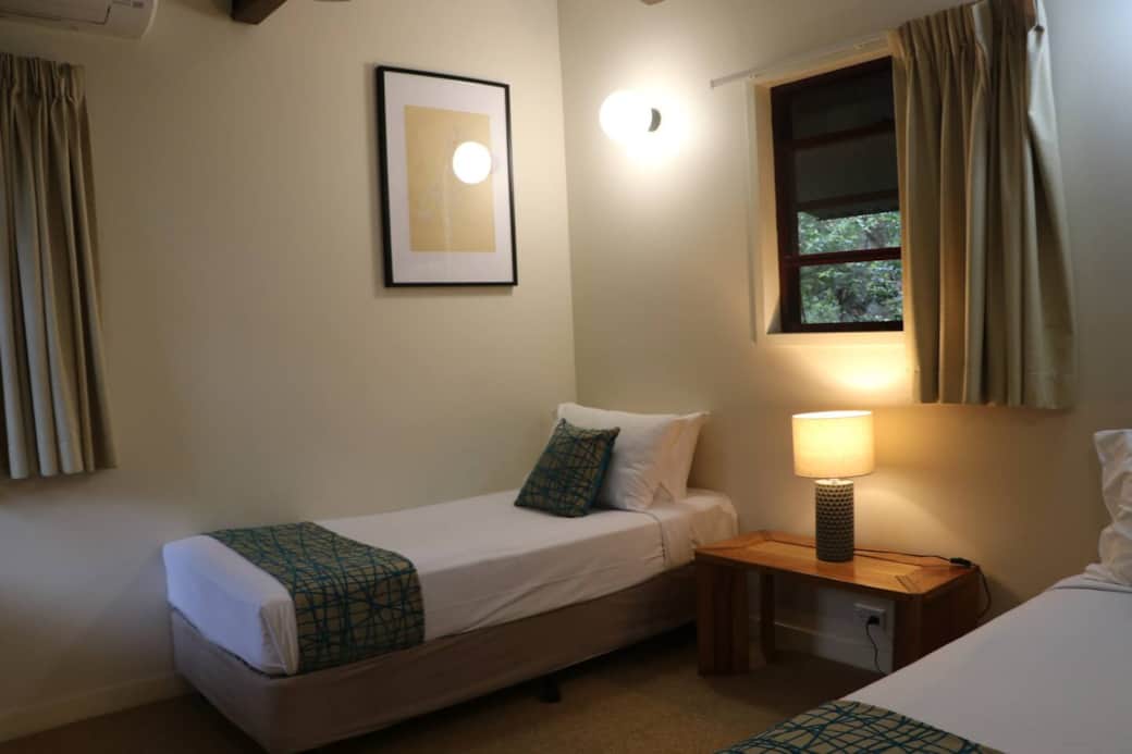 second bedroom with 2 single beds, large built in cupboards, desk seating and airconditioner.