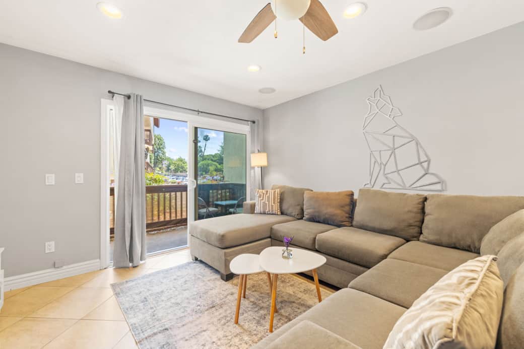 Cozy living room with a large sectional, smart TV, and access to a private balcony.