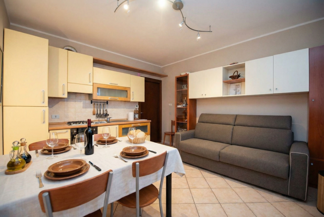 Soggiorno con cucina, tavolo da pranzo e divano letto.