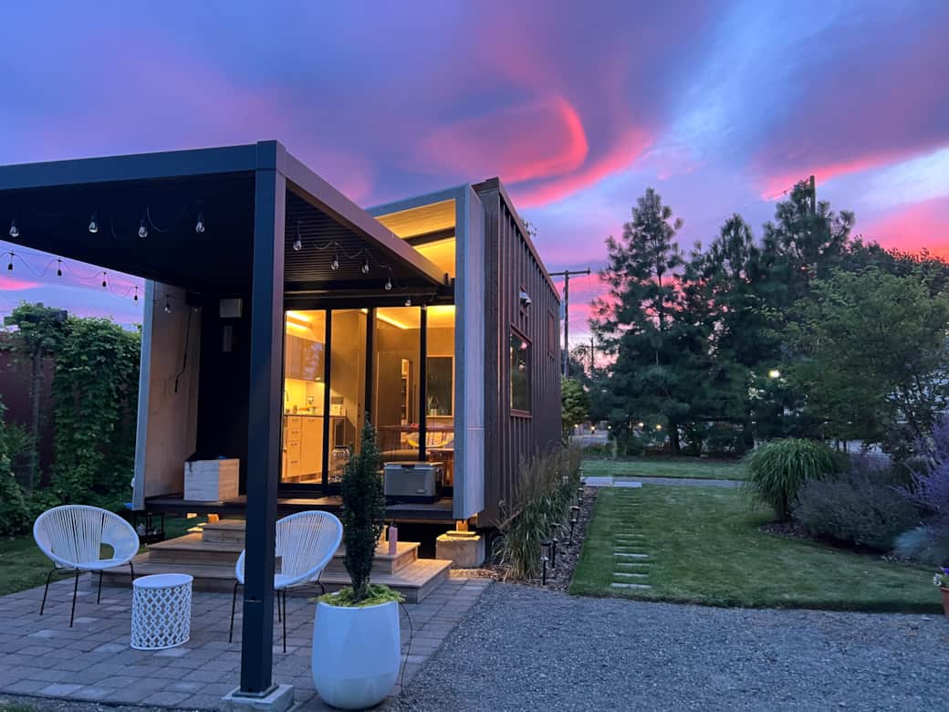 The cabin glows under a vibrant sunset summer sky 
