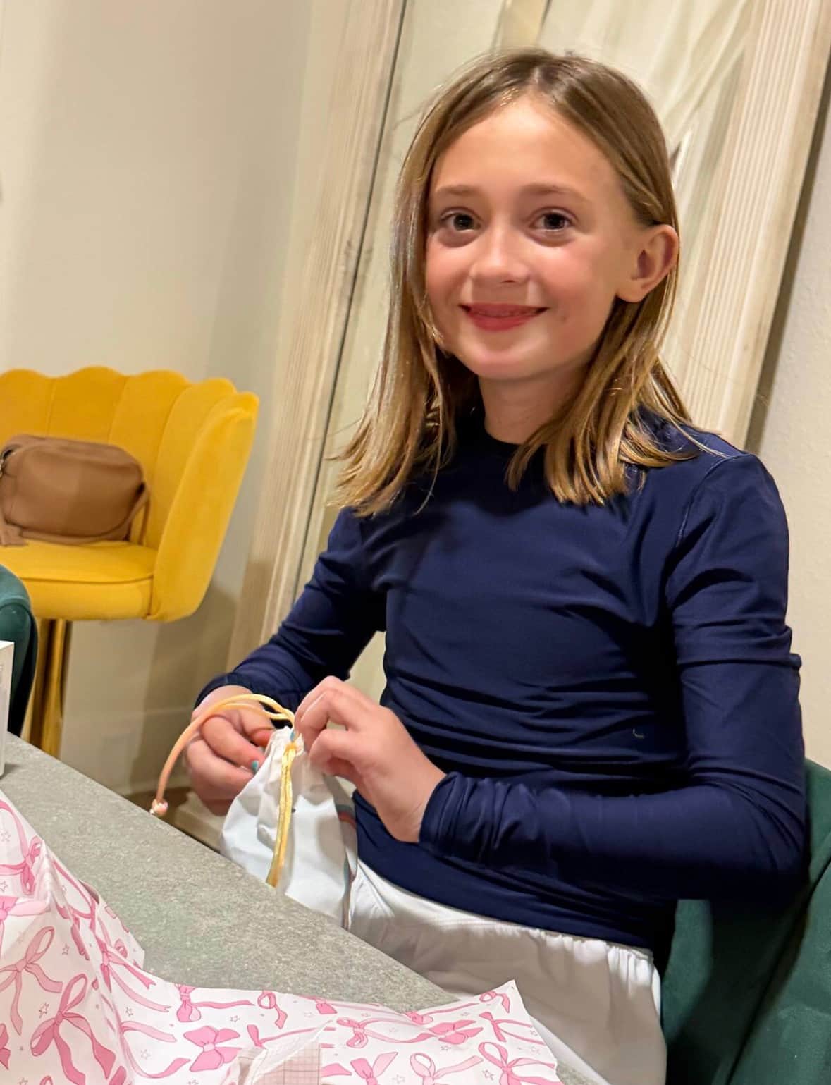 Birthday guest opening gifts at White Magnolia Galveston with the courtyard photo wall glowing in the background