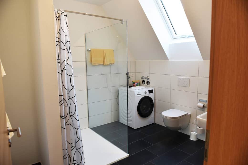 Badezimmer mit großer Dusche und Waschmaschine