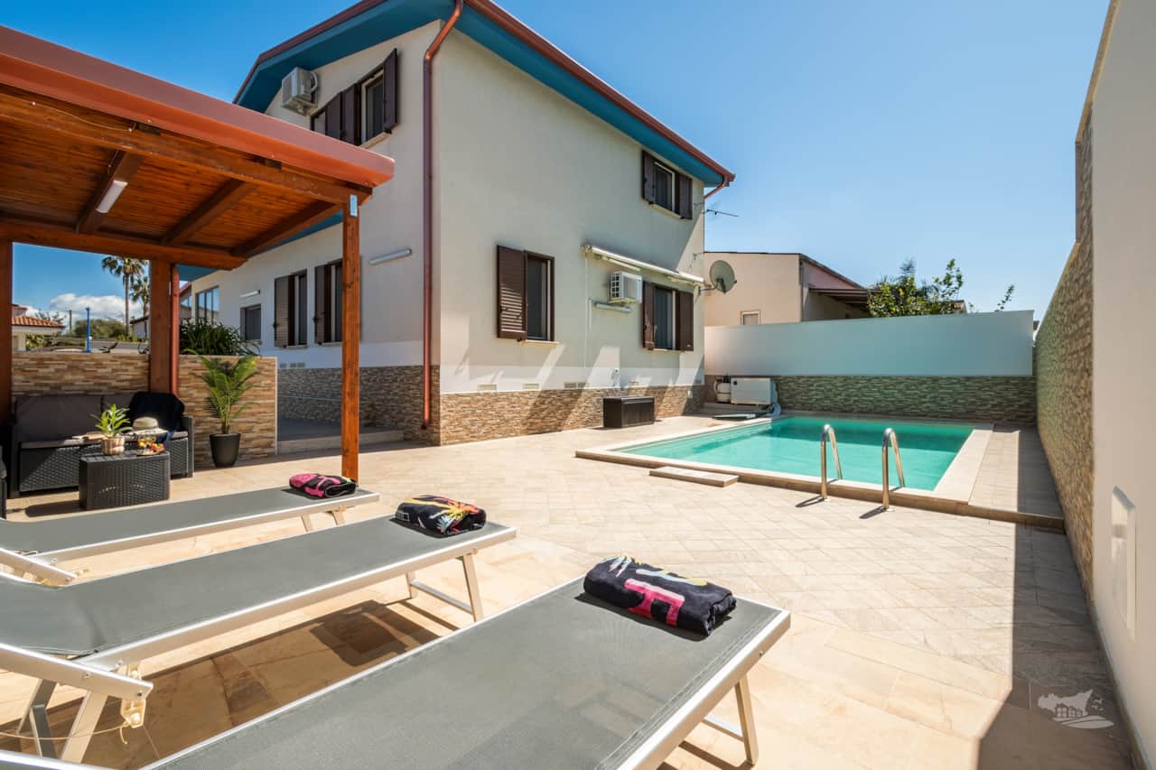 Sun-soaked poolside with loungers, plus a shaded pergola offering cozy seating.