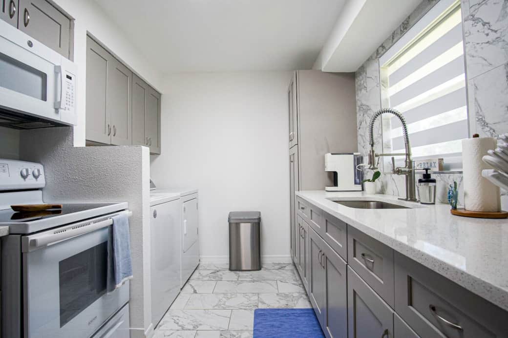Bright, modern kitchen entry with spacious counters, touchless trash can, and an easy, functional layout for cooking and prep.