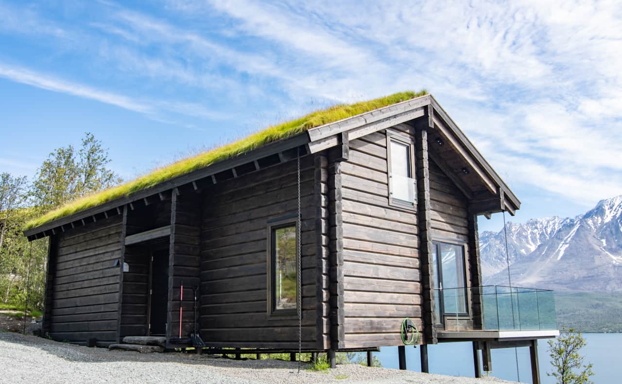 Nordlys cabin exterior with grass roof and Lyngen Alps, Ulsfjord Norway