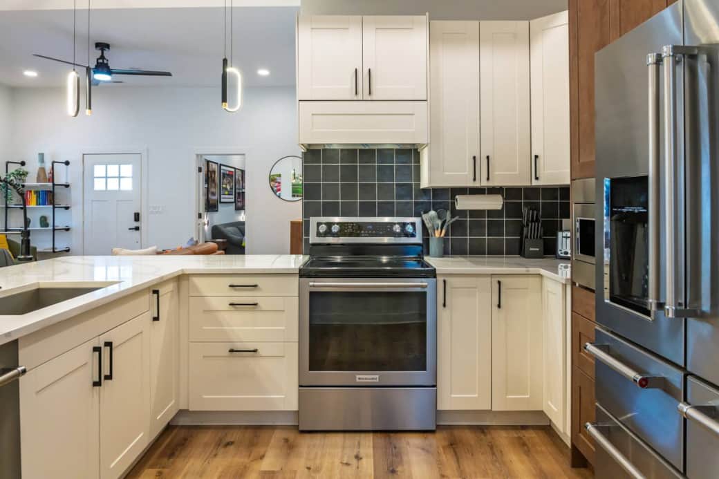 Modern, sleek well-stocked kitchen with white quartz countertops, range with convection oven, microwave, dishwasher, and full-size fridge for a seamless dining experience.