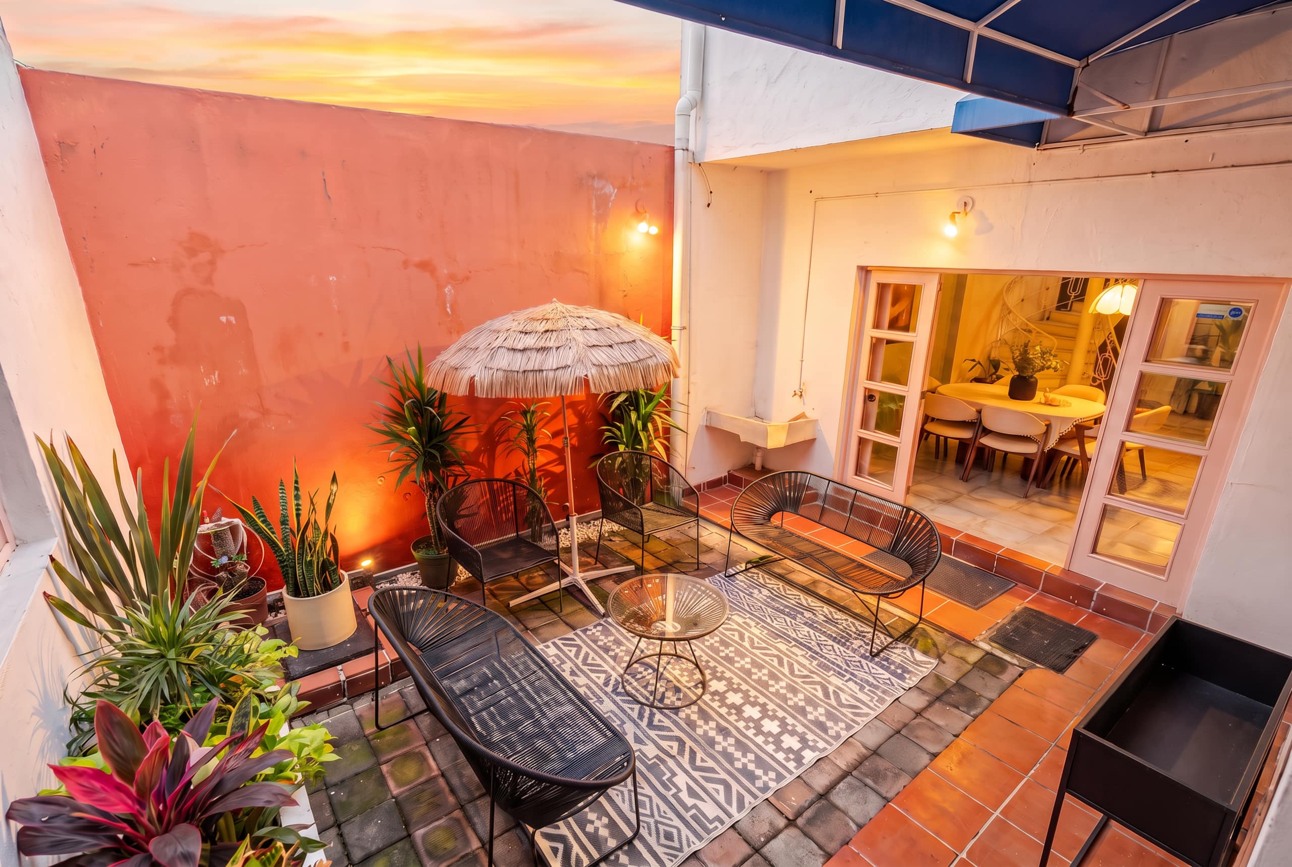 Planted courtyard with a palapa parasol and seating at sunset, with french doors to the dining room at Casa Atlixco