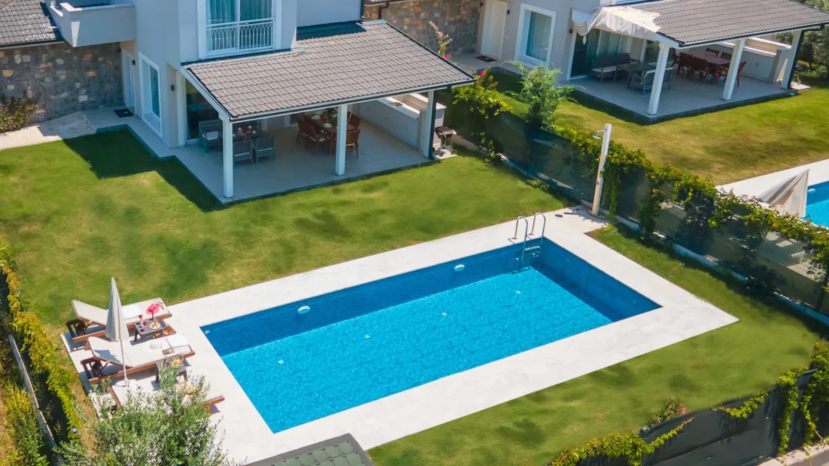 Aerial view of a private pool surrounded by green grass and lounge chairs at Villa Nergis 2 in Göcek.