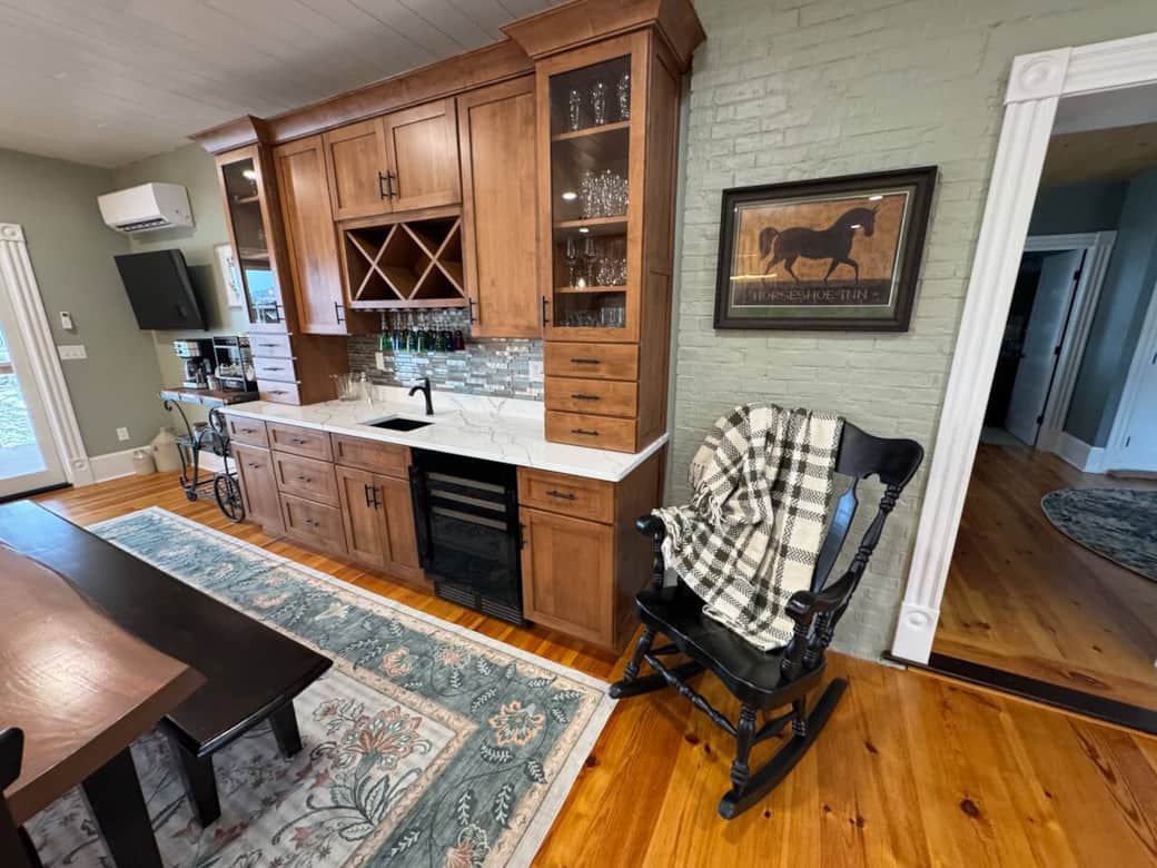 Gather in this luxury farmhouse kitchen featuring island seating, a large dining table, and a full beverage bar.