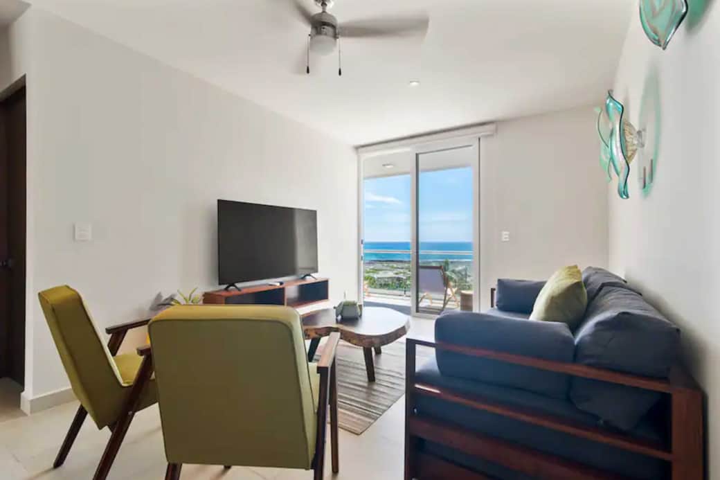 Cozy living room with sofa bed, TV, and balcony with Caribbean views.