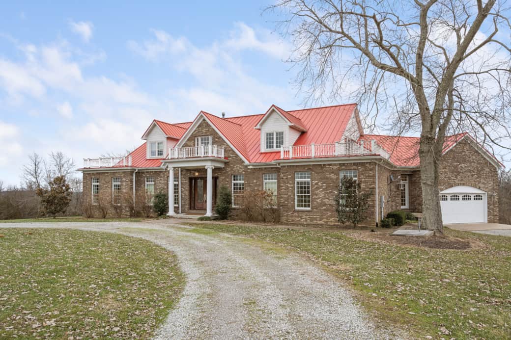 Exterior of brick home with bright red roof, wraparound balconies, and attached garage. Exterior of brick home with bright red roof, wraparound balconies, and attached garage.